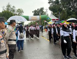 Diguyur Hujan Lebat, Personel Polres Bintan Tetap Lakukan pengamanan Lomba Gerak Jalan Tingkat Kabupaten Bintan.